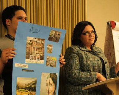man and woman standing at a podium. the man is holding up a poster with pictures that says 'dream'.